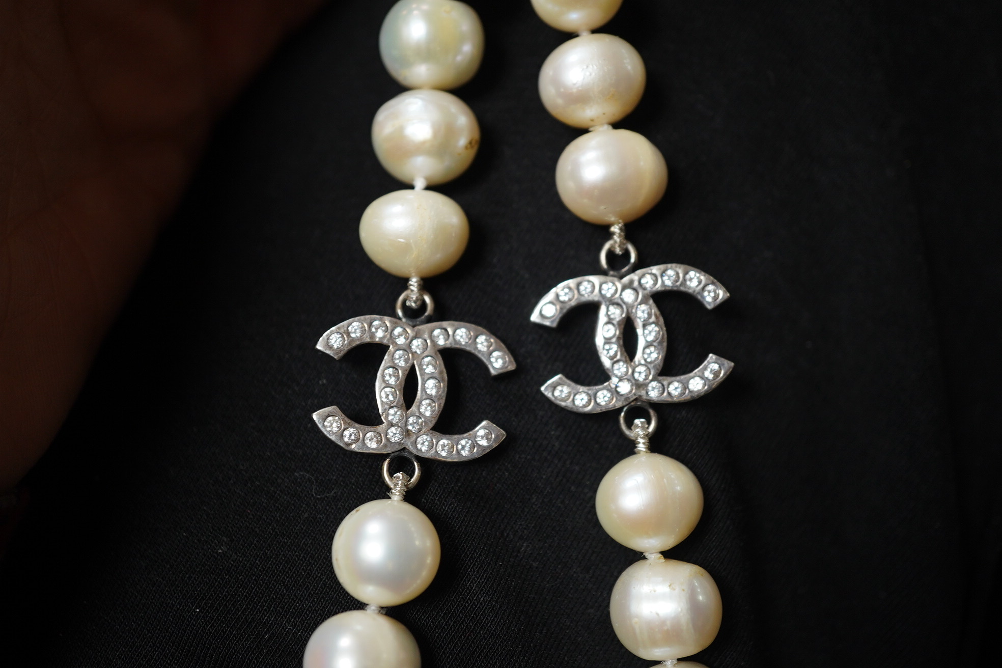 A modern long single strand cultured pearl necklace, with paste set white metal 'double C' clasps, 124cm. Condition - fair